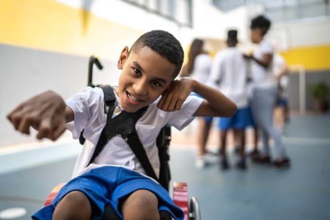 Young boy in wheelchair, smiling and reaching out