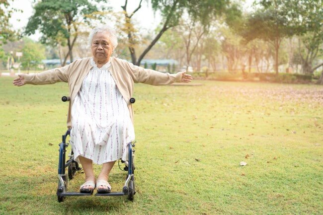 Older Asian woman in a wheelchair with her arms outstretched
